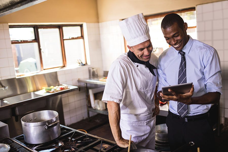 Specialized Business Insurance - Restaurant Manager and Chef Using Tablet in the Kitchen